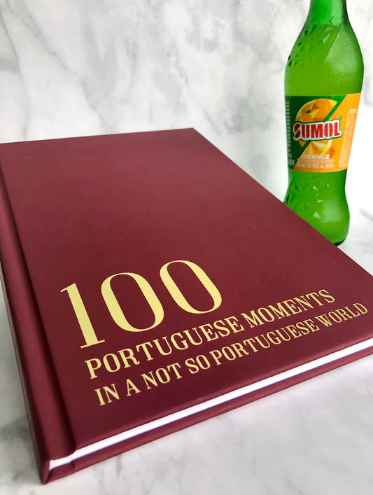 ed book titled '100 Portuguese Moments' with a Sumol bottle on a white background